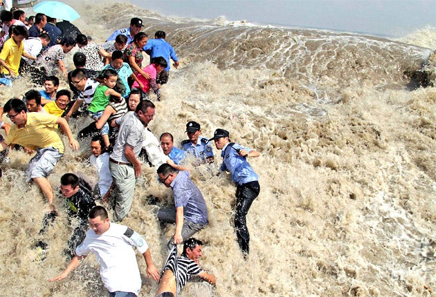 Residents and police run for their lives as a tidal wave bursts the banks of the Qiantang River in Zhejiang province
