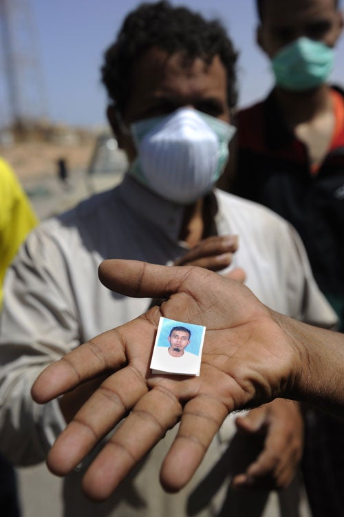 A member of the Transitional National Council's forces shows a photo that was found on a body buried near Bir Umm al-Khanafis