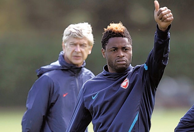 Arsène Wenger looks on as Alex Song gestures during a training session before the team's departure