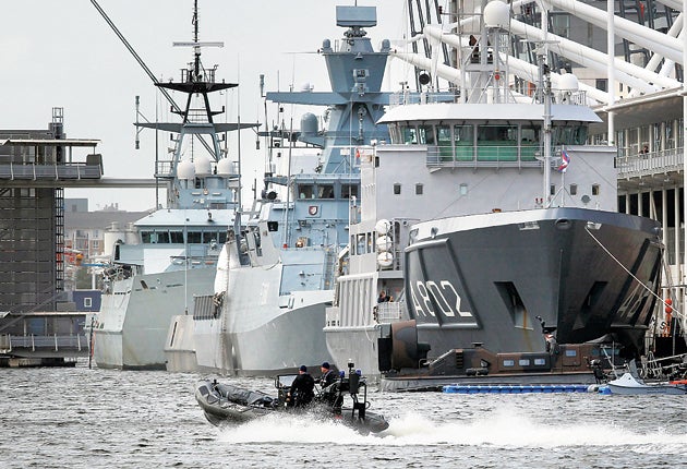 A police boat passes naval vessels at the ExCeL centre
