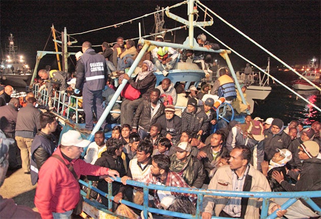Italian coastguards look on as African refugees arrive on Lampedusa