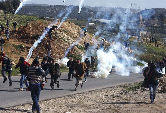 Palestinian protesters run from tear gas fired by Israeli troops in Nabi Saleh in January 2010