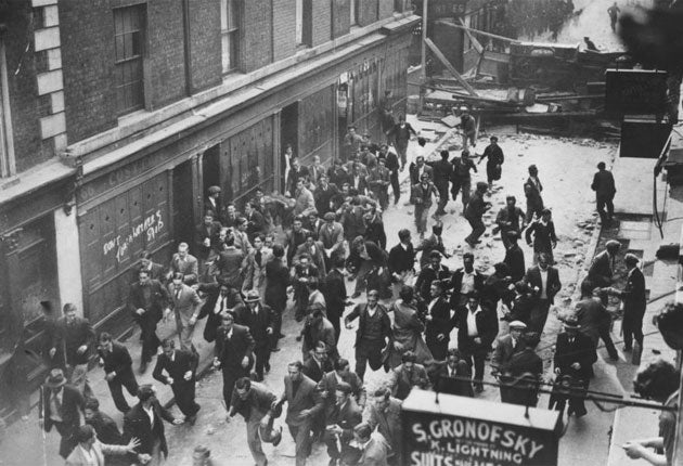 A crowd of demonstrators fleeing as police break down a barricade in Cable Street