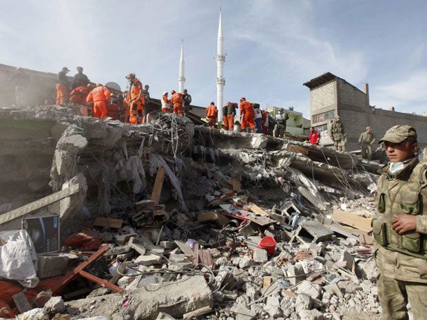 Soldiers stand near rescue workers as they try to save people trapped under debris following the earthquake. Reuters