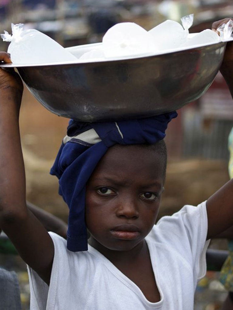 Sorie Sesay, 10, carries packets of water to sell in Freetown