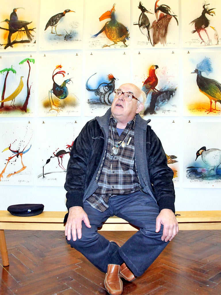 The artist Ralph Steadman sits amid his paintings