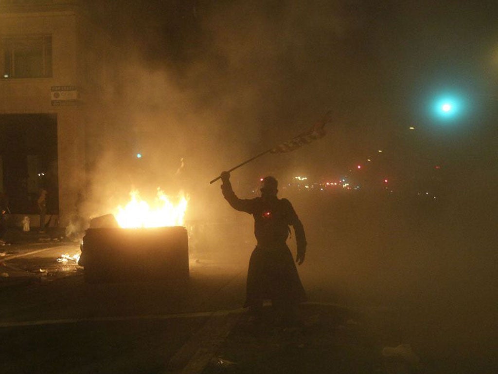An Occupy Oakland protester waves a flag next to a bonfire