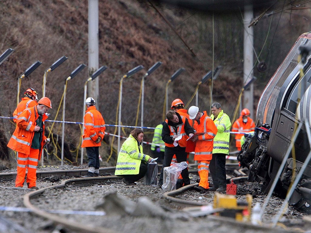 Rail workers examine the scene of the 2007 Virgin train crash at Grayrigg in Cumbria