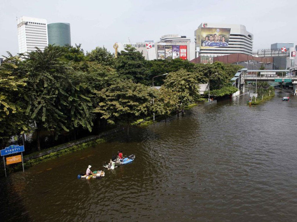 Residents use make-shift rafts to travel along a flooded street in Bangkok