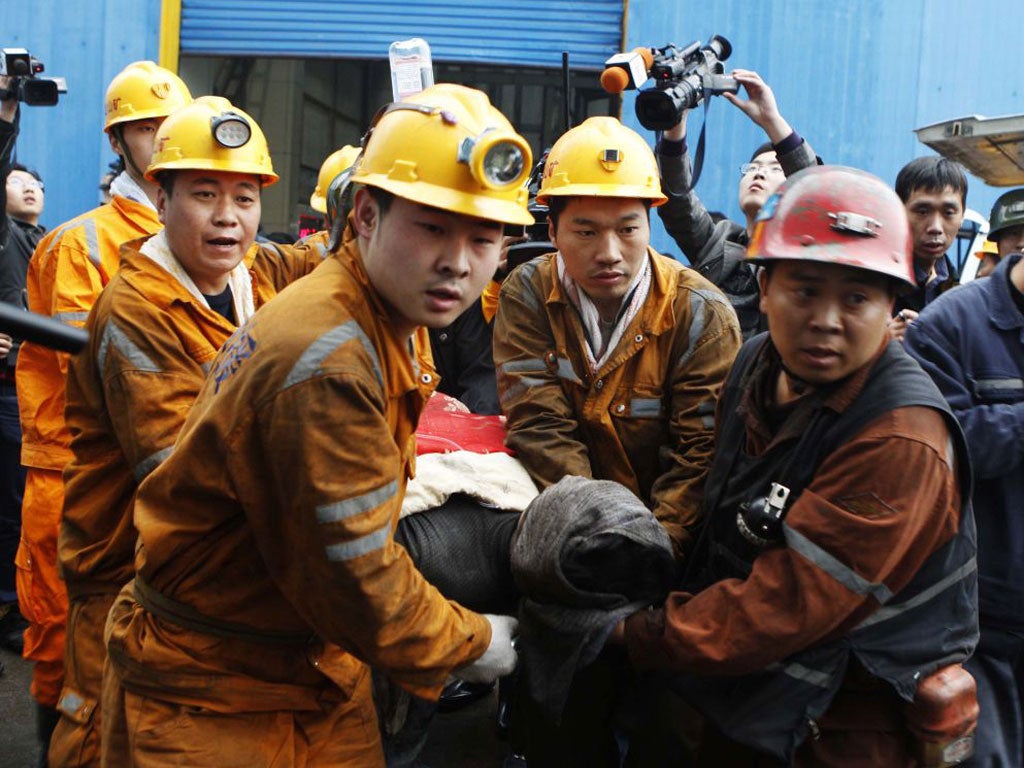 Chinese rescuers carry out one of the rescued miners from the Qianqiu colliery