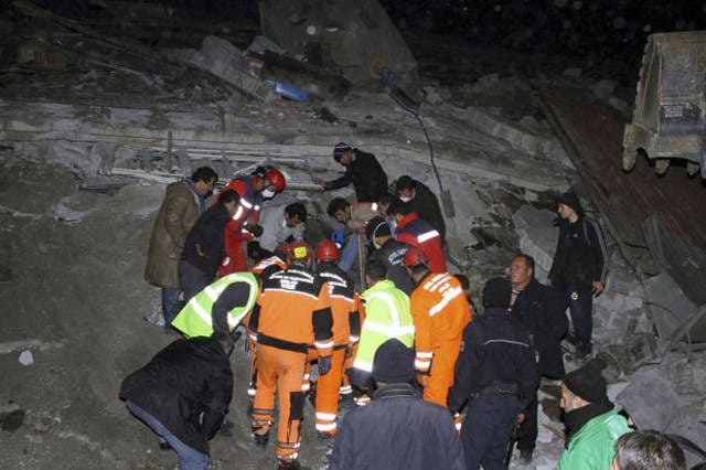 Rescue workers search for survivors in the rubble of a collapsed building in Van