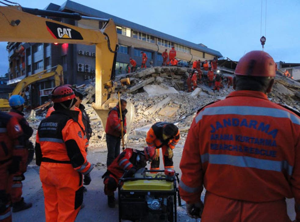Turkish rescue workers search for survivors in the rubble of a collapsed hotel in Van