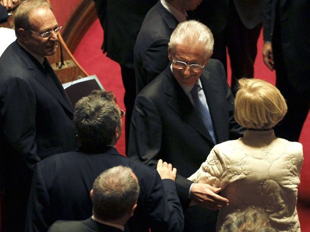 Former European Commissioner Mario Monti (second right) is greeted by senators as he arrives for the vote