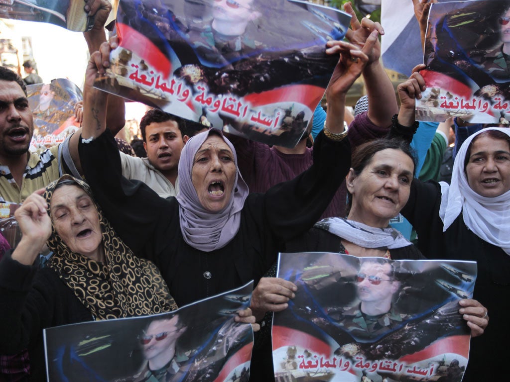 Pro-regime protesters hold up posters of Bashar al-Assad