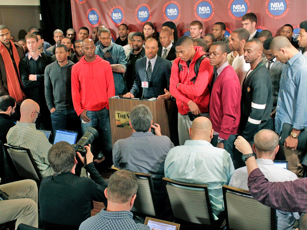 Players' association president Derek Fisher is surrounded by NBA players at a news conference following a meeting of the players' union in New York