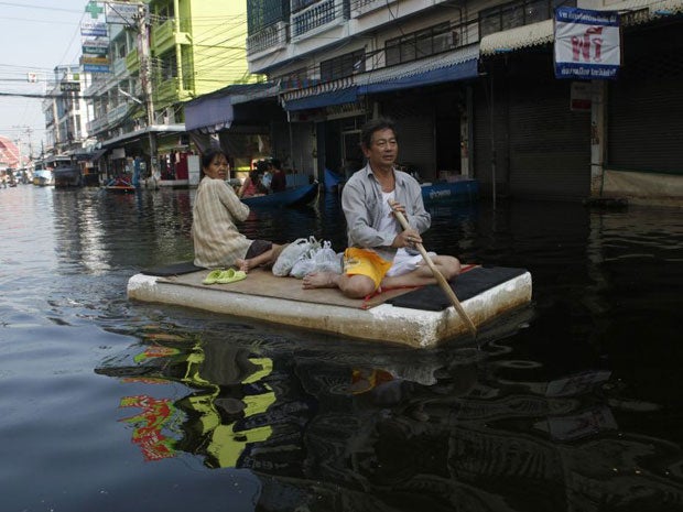 Residents paddle a makeshift raft through a flooded street in Bangkok