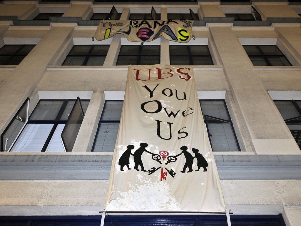 Occupy protesters hang banners from an empty office block owned by UBS bank building in London