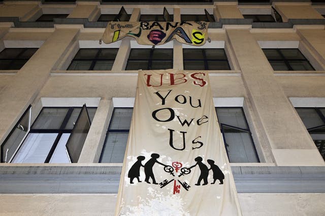 Occupy protesters hang banners from an empty office block owned by UBS bank building in London