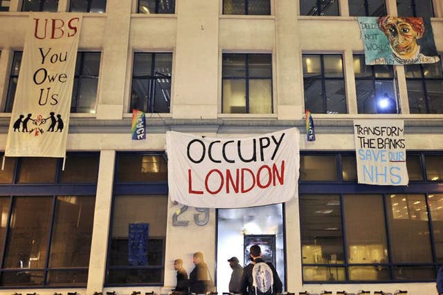 Occupy protesters hang banners from an empty office block owned by UBS bank in London
