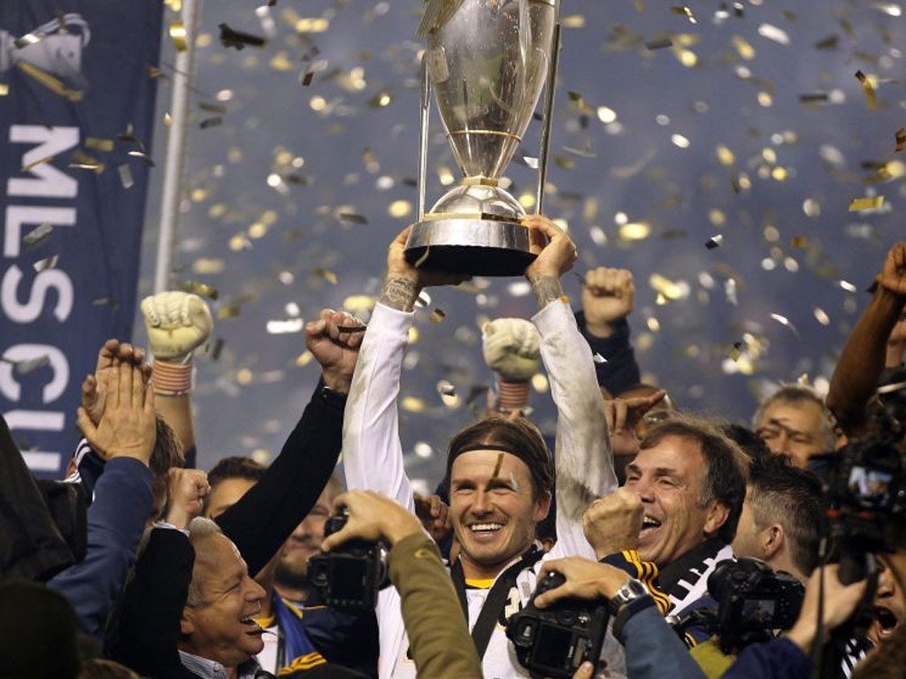 Los Angeles Galaxy's David Beckham hoists the championship trophy as the team celebrate their victory over the Houston Dynamo