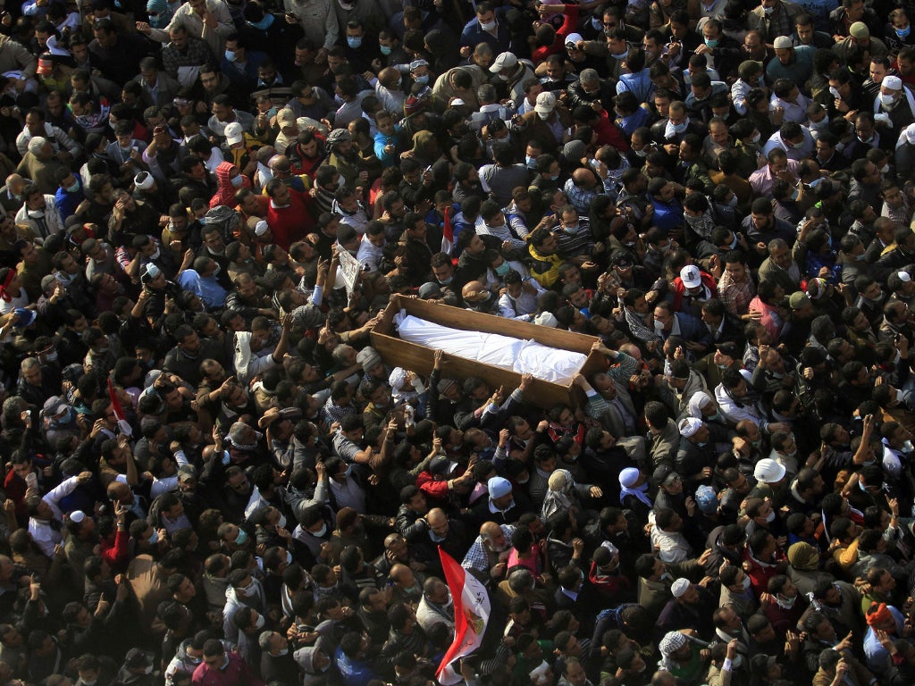 Protesters carry a body of a civilian killed in clashes with police at Tahrir Square in Cairo