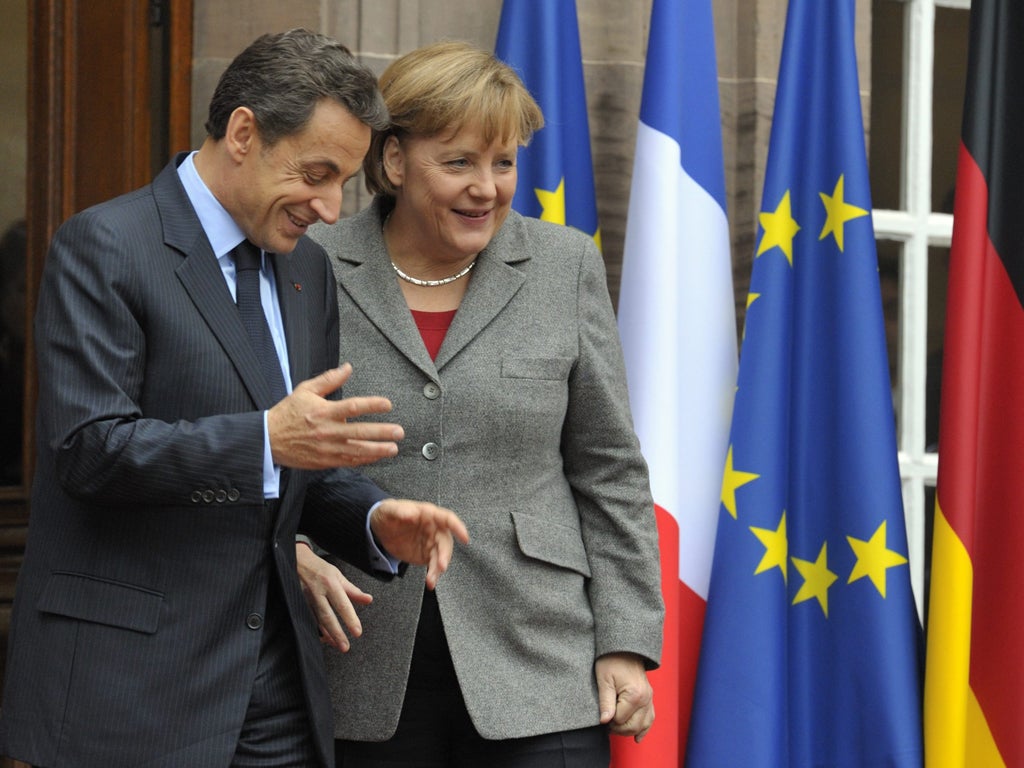Nicolas Sarkozy speaks with Angela Merkel following a trilateral meeting on eurozone crisis with Italian Prime Minister Mario Monti in Strasbourg