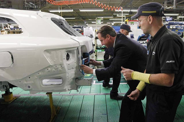Prime Minister David Cameron installs a badge on a car at a Toyota plant in Burnaston in the East Midlands yesterday
