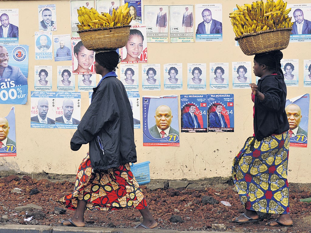 Congolese women carrying baskets of bananas pass election campaign posters in Goma yesterday