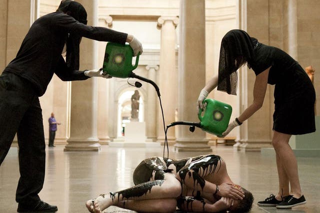 Activists from Liberate Tate pouran oil-like substance over a naked group member in the middle of the Tate Britain