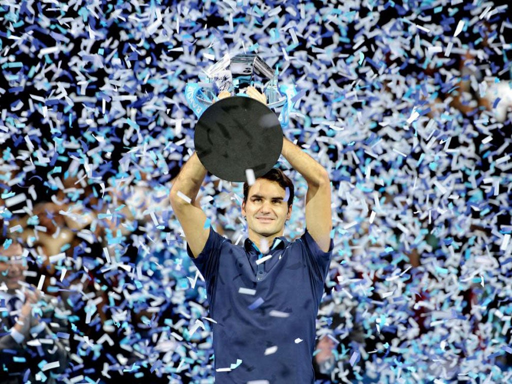 Roger Federer is showered in ticker-tape after receiving the World Tour Finals trophy