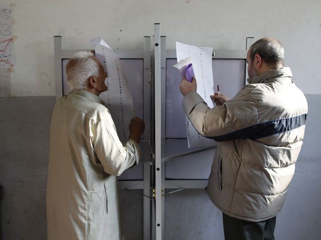 Egyptians read their ballots at a booth before casting their votes at a polling station
