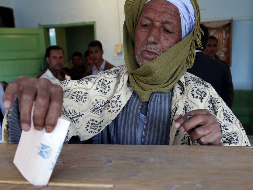 An Egyptian man casts his vote in a polling station in El Aal village south of Assuit, 320 kilometers (200 miles) south of Cairo