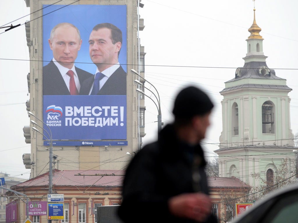 A man walks past by a huge Parliamentary election campaign poster of the United Russia ruling party depicting President Dmitry Medvedev and Prime Minister Vladimir Putin, in Moscow