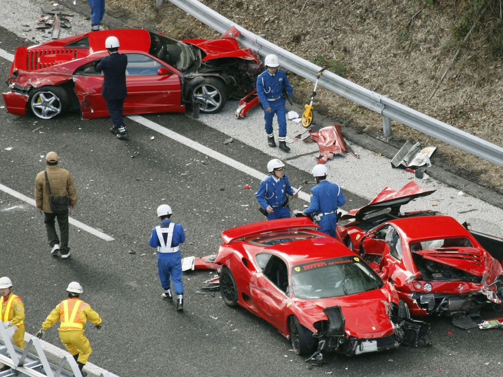 Police officers investigate damaged Ferrari cars at the site of a traffic accident on the Chugoku Expressway in Shimonoseki, southwestern Japan