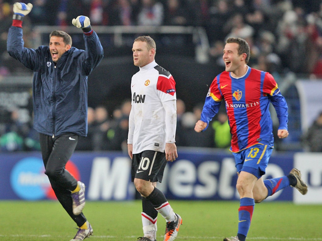 Wayne Rooney cuts a disconsolate figure as the Basle players celebrate at the final whistle last night