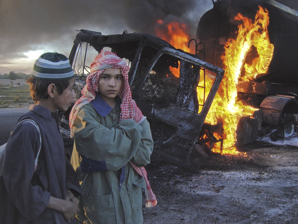 Two boys stand beside fuel trucks as gunmen fire on trucks stranded by Nato blockade