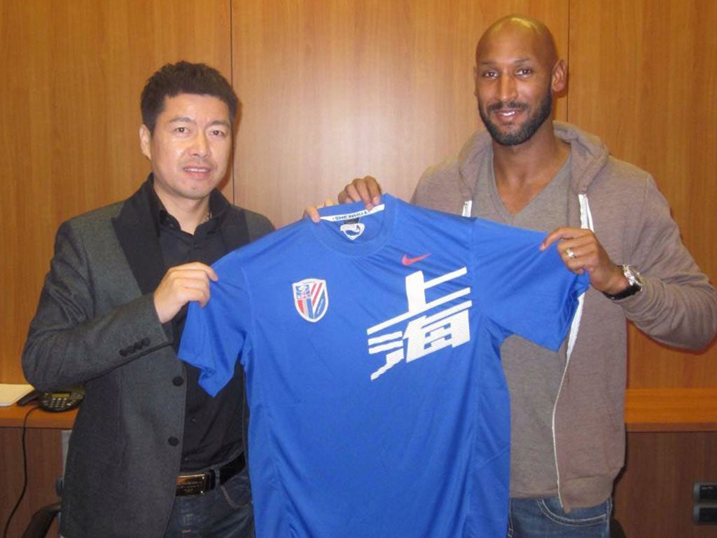 Nicolas Anelka (right) poses with his new shirt and Shanghai Shenhua club investor Zhu Jun after signing a two-year deal