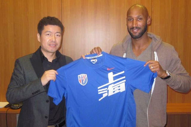 Nicolas Anelka (right) poses with his new shirt and Shanghai Shenhua club investor Zhu Jun after signing a two-year deal