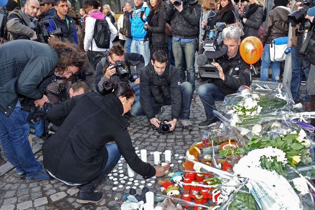 People display candles in a broken bus shelter, one of the targets of the shooting on the Place Saint-Lambert in Liege