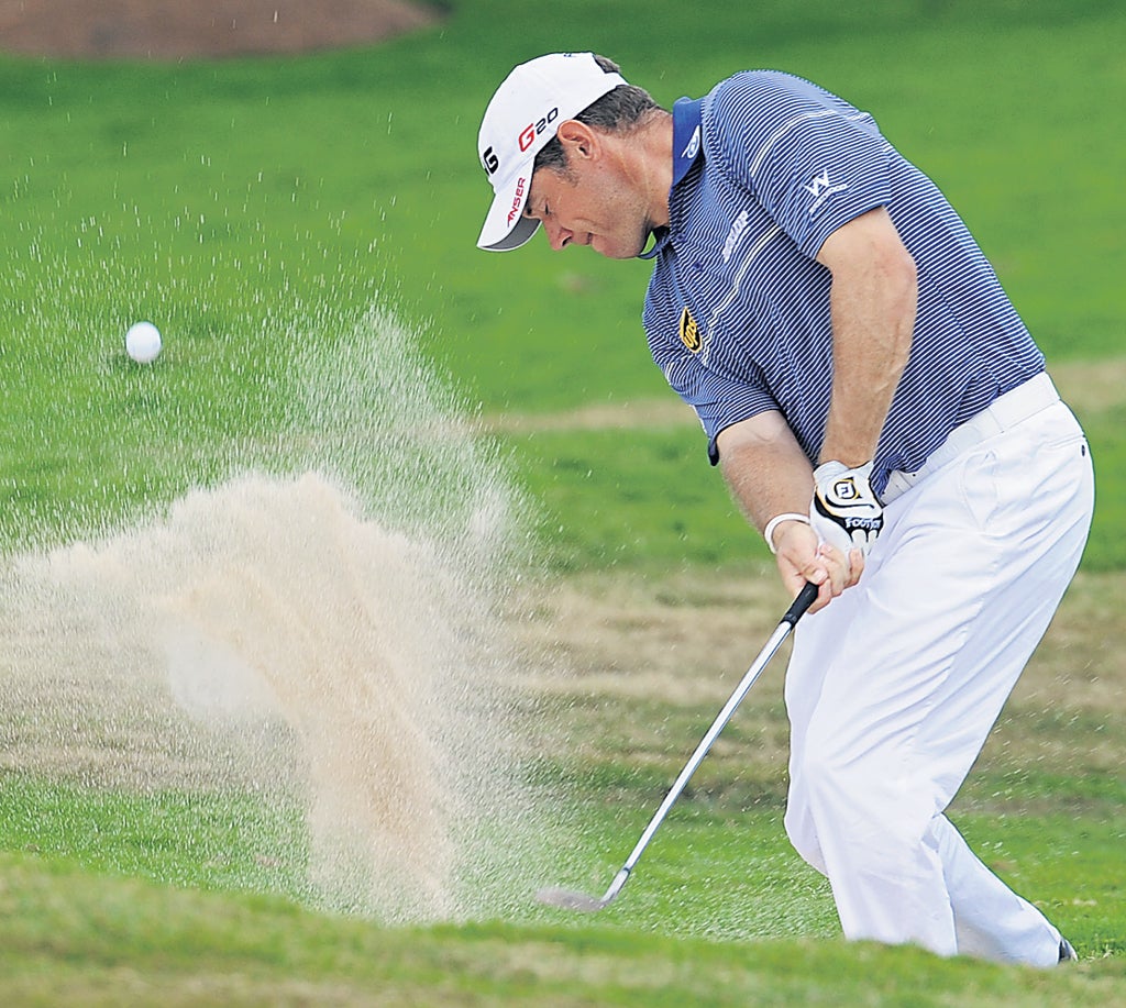 Trap negotiated: Lee Westwood splashes out of a bunker during his third-round 73 in Bangkok yesterday