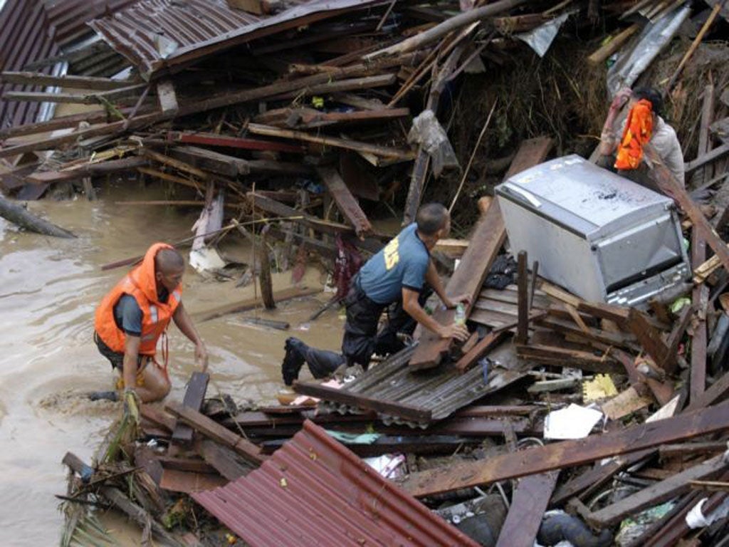 Police approach a distraught resident following a flash flood that inundated Cagayan de Oro city, Philippines