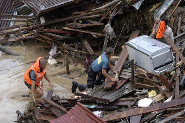 <p>Police approach a distraught resident following a flash flood that inundated Cagayan de Oro city, Philippines</p>