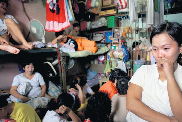 <p>Overcrowded and insanitary: A woman stands in the corner of a female cell, where several dozen inmates are crammed in, at the Navotas Municipal Prison in Manila, Philippines</p>