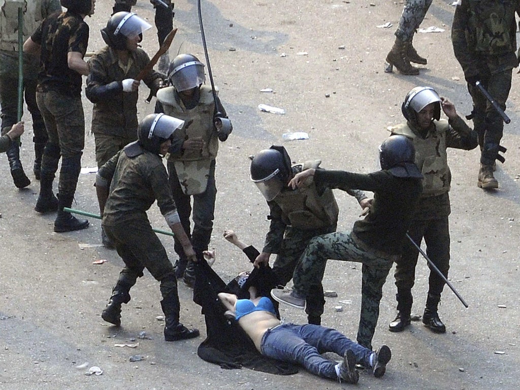 A woman is attacked by police officers in Tahrir Square, revealing her bra at one point