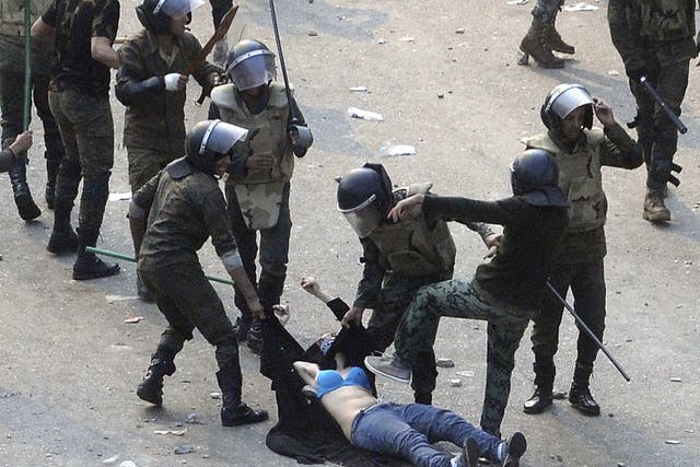 <p>A woman is attacked by police officers in Tahrir Square, revealing her bra at one point</p>