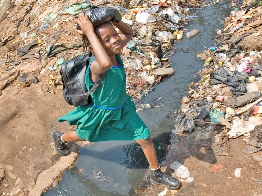 A schoolgirl jumps over an open sewer in Kroo Bay, Sierra Leone