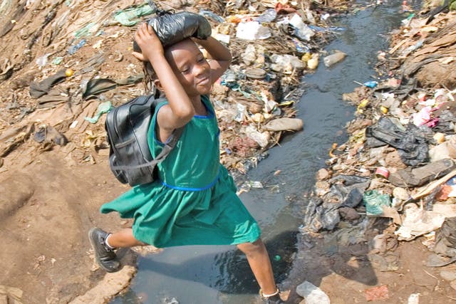 <p>A schoolgirl jumps over an open sewer in Kroo Bay, Sierra Leone</p>