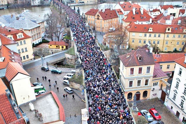A procession of mourners crosses the Charles Bridge in Prague