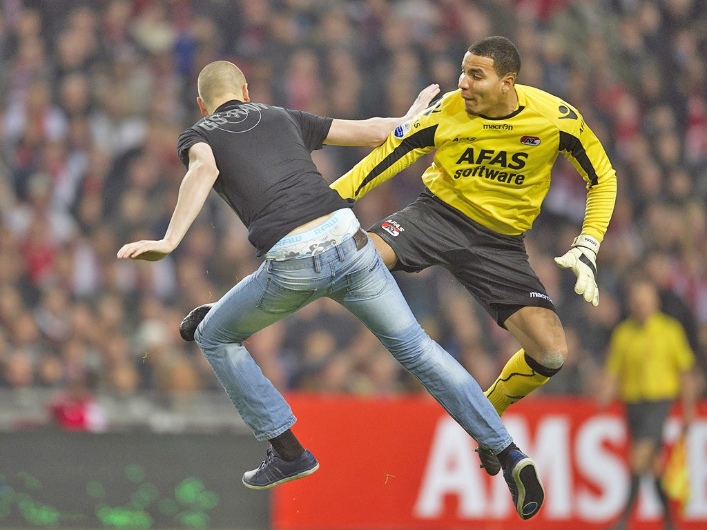 Goalkeeper Esteban of AZ kicks a pitch invader who attacked him during their football cup match against Ajax