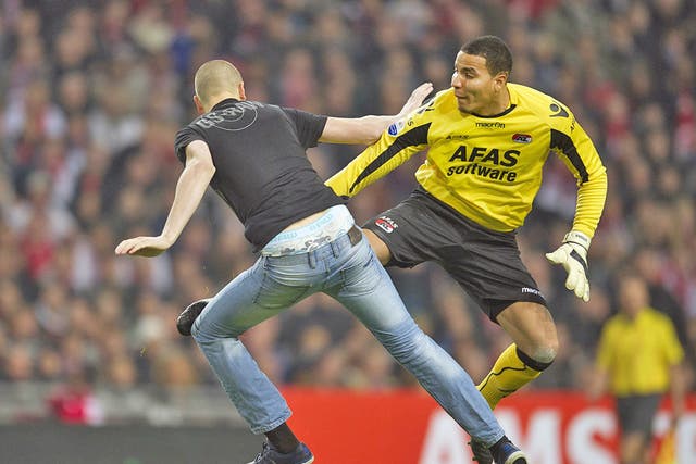 Goalkeeper Esteban of AZ kicks a pitch invader who attacked him during their football cup match against Ajax 